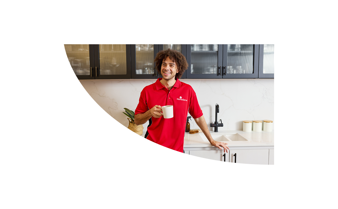 A smiling HomeServe plumber holding a cup of tea